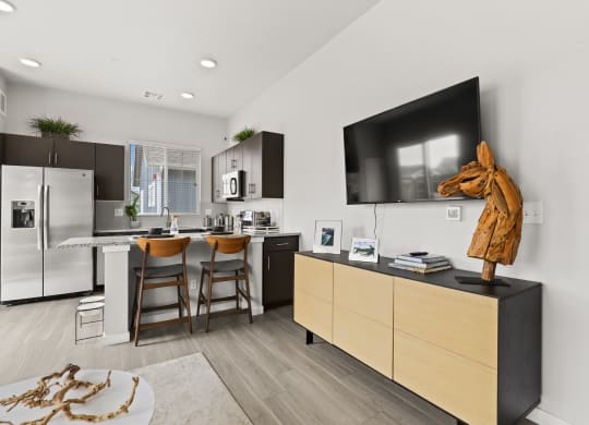 a kitchen and living room with a large tv on the wall and a wooden horse statue on
