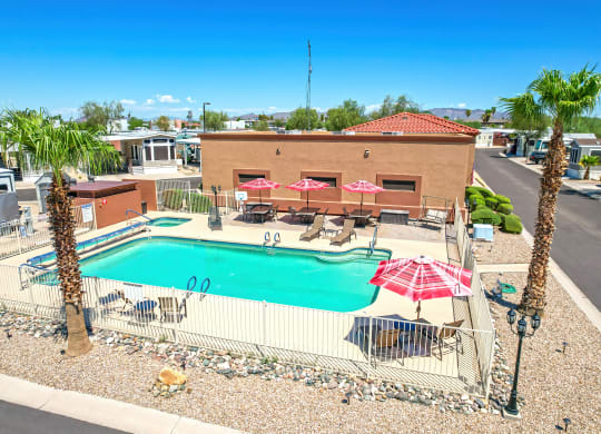 an aerial view of a swimming pool with umbrellas and a resort style building