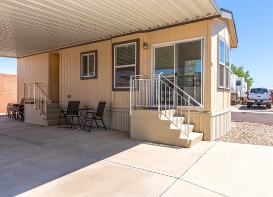 the front of a house with stairs and a patio with chairs