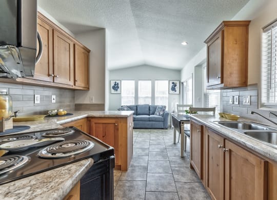 the kitchen and living room of a house with wood cabinets