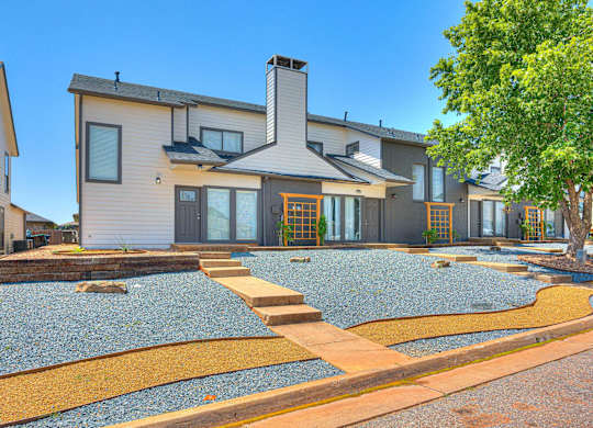 A modern house with a grey roof and a stone pathway leading to the front door.