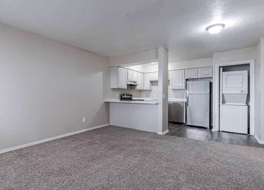 A kitchen area with white appliances and a grey carpet.