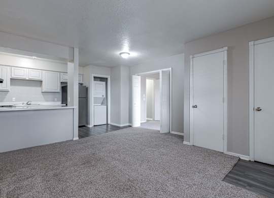A spacious, empty room with white walls and carpeted floor.