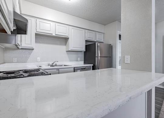 A kitchen with white marble countertops and stainless steel appliances.
