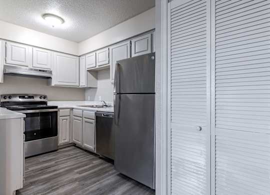 A kitchen with a stove, sink, and refrigerator.