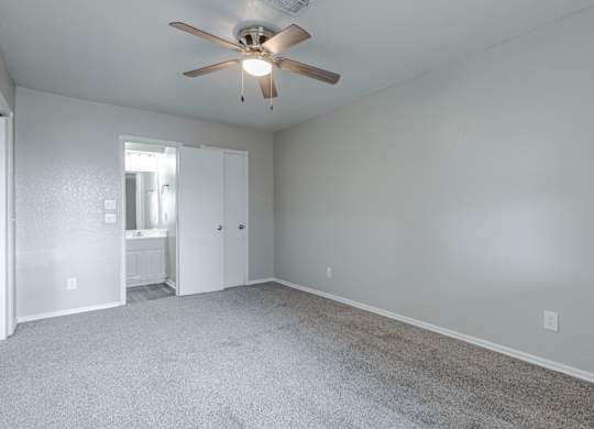 A room with a ceiling fan and carpeted floor.
