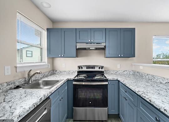 A kitchen with blue cabinets and granite countertops.
