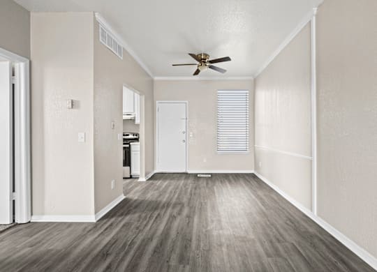 A room with a ceiling fan and wooden flooring.