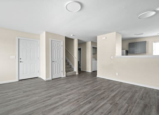 A spacious room with wooden floors and white walls.