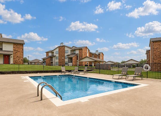 A swimming pool in a residential area with houses in the background.