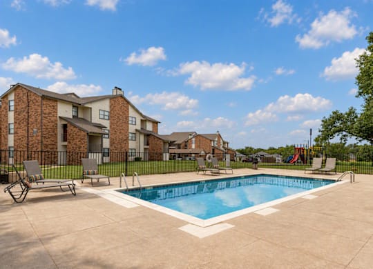 A swimming pool surrounded by a concrete patio and a black fence.