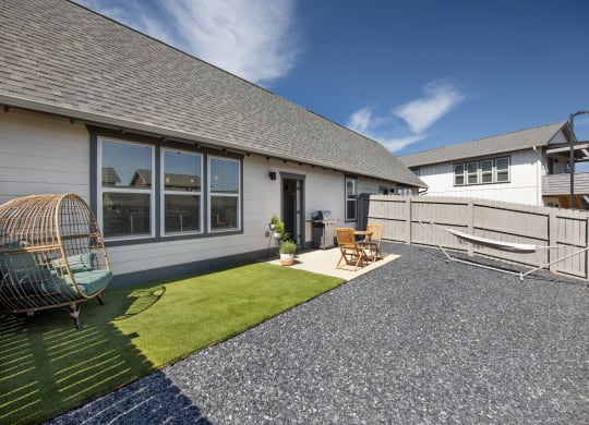a backyard with a fence and a patio with chairs and grass