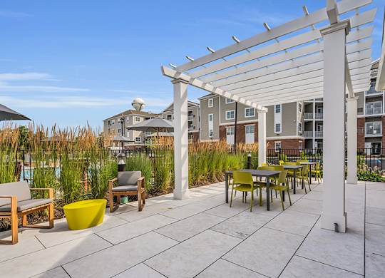 A patio with a white pergola and a yellow planter.