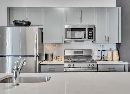 A modern kitchen with a stainless steel refrigerator, microwave, oven, and sink.