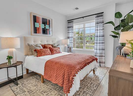 A bedroom with a large bed and a window with curtains.