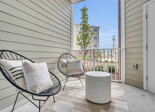 A patio with two chairs and a table with a white pillow on it.