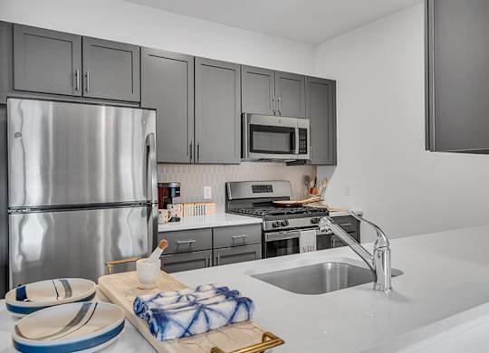 A kitchen with a stainless steel refrigerator, microwave, and oven.