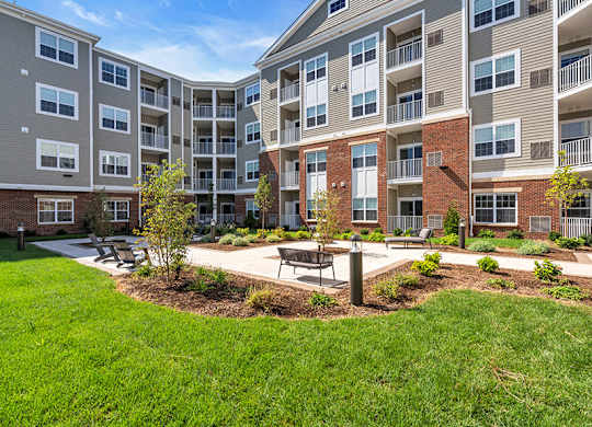 Apartment complex with a green lawn and trees in front.