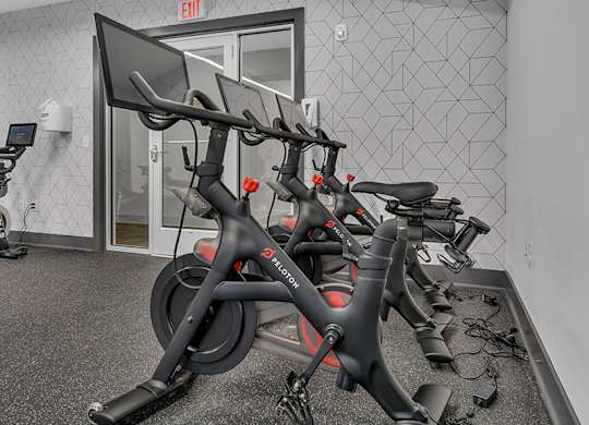 A stationary bike is leaning against a wall in a gym.