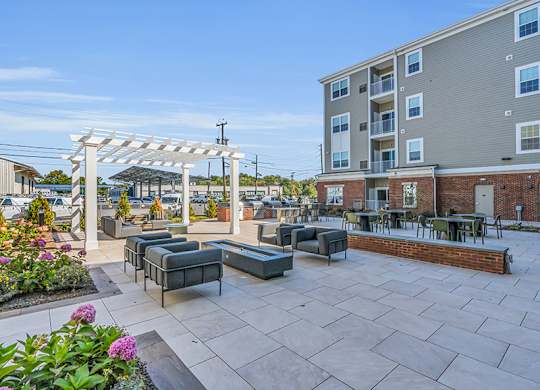 A patio with a white pergola and black furniture.