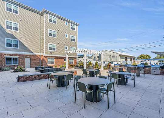 A patio with tables and chairs is surrounded by apartment buildings.