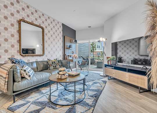 A living room with a grey couch, a round coffee table, and a mirror on the wall.