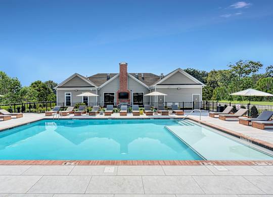 A large swimming pool surrounded by lounge chairs and umbrellas.