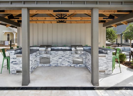 a covered patio with a barbecue grill and chairs
