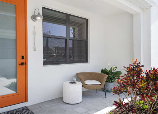 Front patio with a chair in front of an orange door