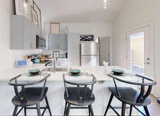 a kitchen with a white counter top and three stools
