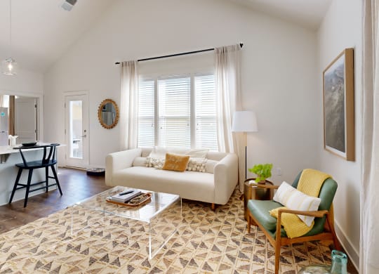 a living room with a couch and a chair and a kitchen with a table