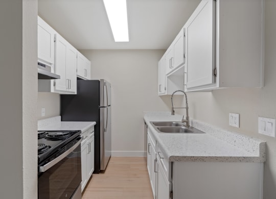 Kitchen with white cabinets and a sink and a refrigerator at Verde Apartments in Tucson, AZ