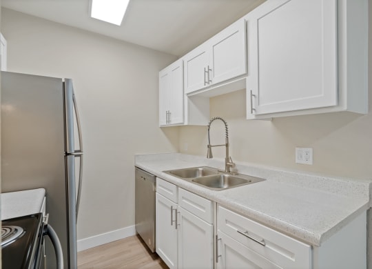 Kitchen with white cabinets and a sink and a refrigerator at Verde Apartments in Tucson.