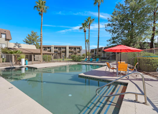 our apartments have a resort style pool with chairs and an umbrella in Tucson.