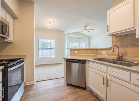 Kitchen with white cabinets and a stainless steel dishwasher at Park Hudson Place Apartments, Texas