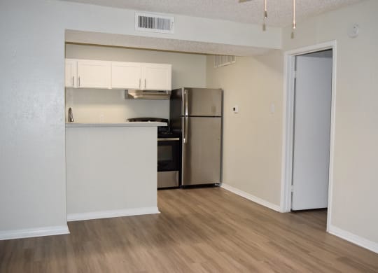 an empty apartment with a kitchen and a refrigerator at The Wick, College Station