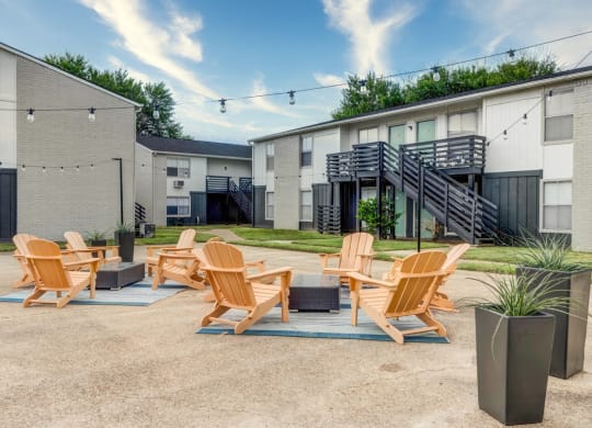 Patio with a fire pit and lounge chairs in front of an apartment building  at The Wick, College Station