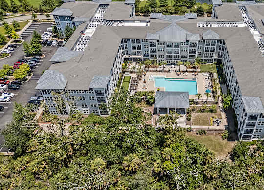 An aerial view of a large building complex with a pool in the center.