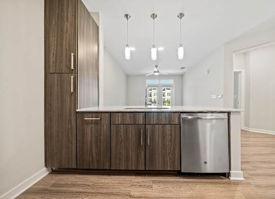 A kitchen with wooden cabinets and a stainless steel dishwasher.