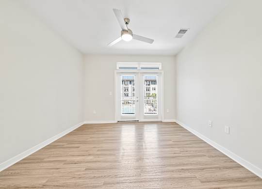 A room with a ceiling fan and wooden flooring.