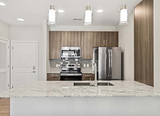 A modern kitchen with a marble countertop and stainless steel appliances.