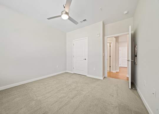 A room with a ceiling fan and carpeted floor.
