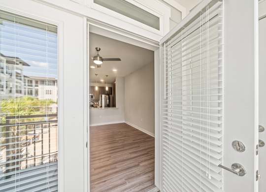 A white door with a glass window is open to a room with a ceiling fan.