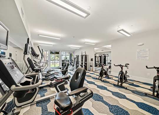 A gym with a variety of exercise equipment including treadmills, stationary bikes, and weight machines.