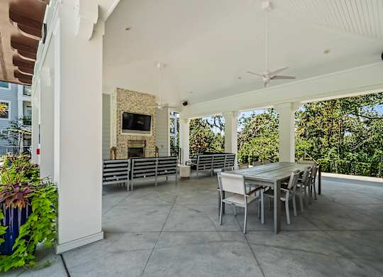 A patio with a table and chairs and a ceiling fan.