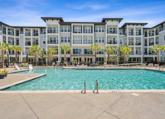 A large swimming pool in front of a multi-story apartment building.
