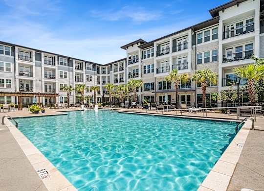 A large swimming pool in front of a multi-story apartment building.