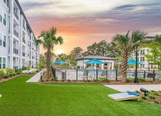 A sunset view of a residential area with apartment buildings and a pool.