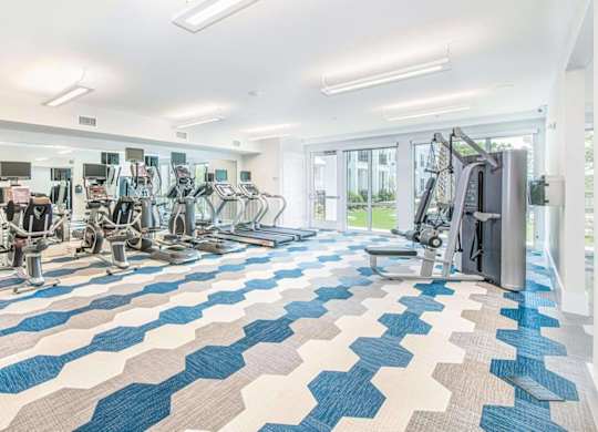 A gym with a variety of equipment including treadmills, weights, and exercise machines.