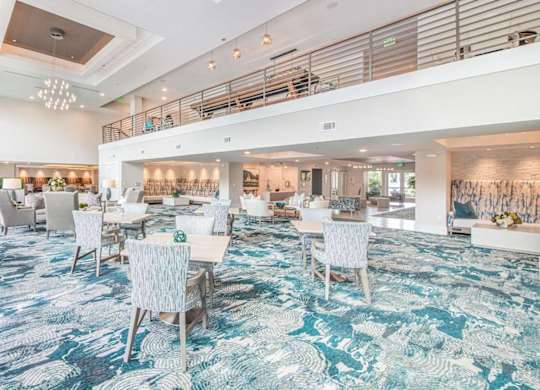 A spacious dining area with a carpeted floor and white chairs.